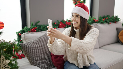 Poster - Young beautiful hispanic woman make photo by smartphone to christmas tree at home