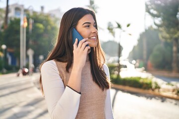 Wall Mural - Young beautiful hispanic woman smiling confident talking on the smartphone at street