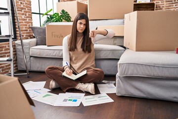 Poster - Young brunette woman moving to a new home doing finances with angry face, negative sign showing dislike with thumbs down, rejection concept