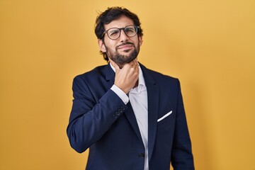 Poster - Handsome latin man standing over yellow background touching painful neck, sore throat for flu, clod and infection