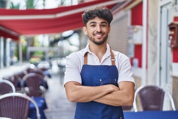 Sticker - Young arab man waiter standing with arms crossed gesture at restaurant