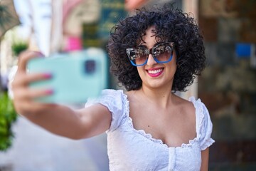 Wall Mural - Young middle east woman smiling confident make selfie by smartphone at street