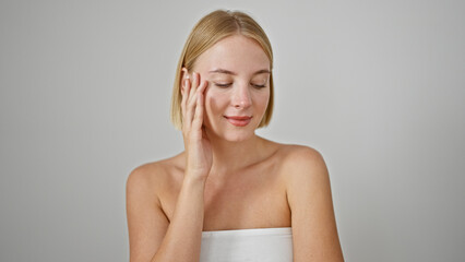 Wall Mural - Young blonde woman smiling confident touching face over isolated white background