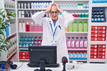 Poster - Young caucasian woman working at pharmacy drugstore suffering from headache desperate and stressed because pain and migraine. hands on head.