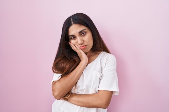 Young arab woman standing over pink background thinking looking tired and bored with depression problems with crossed arms.