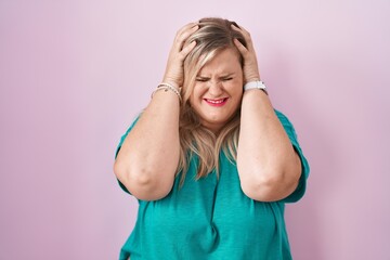 Poster - Caucasian plus size woman standing over pink background suffering from headache desperate and stressed because pain and migraine. hands on head.