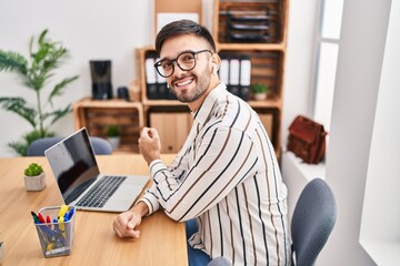 Canvas Print - Young hispanic man business worker using laptop and earphones at office