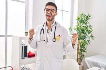 Poster - Hispanic man wearing doctor uniform and stethoscope celebrating surprised and amazed for success with arms raised and eyes closed