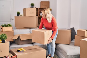 Canvas Print - Young blonde woman smiling confident holding package at new home