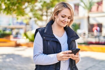 Canvas Print - Young blonde woman smiling confident using smartphone at park