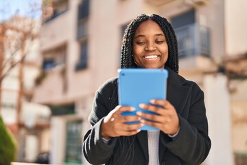 Wall Mural - African american woman smiling confident using touchpad at street