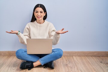 Canvas Print - Young woman using laptop sitting on the floor at home smiling cheerful with open arms as friendly welcome, positive and confident greetings