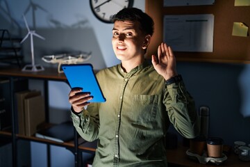 Wall Mural - Non binary person using touchpad device at night waiving saying hello happy and smiling, friendly welcome gesture