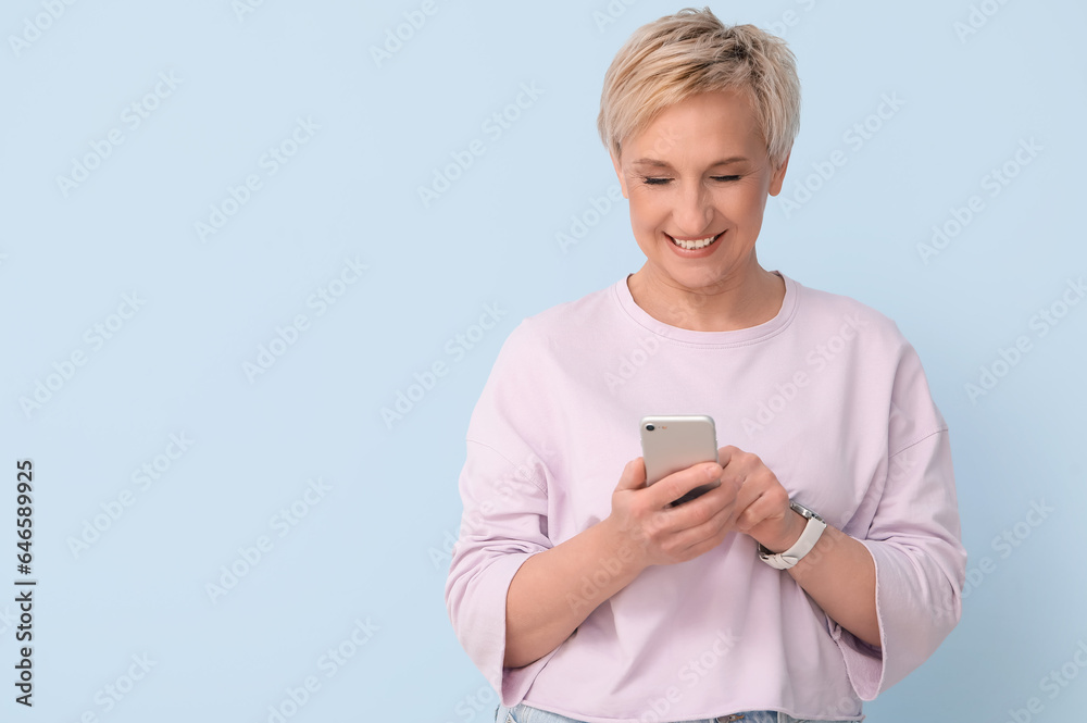 Mature woman using mobile phone on blue background
