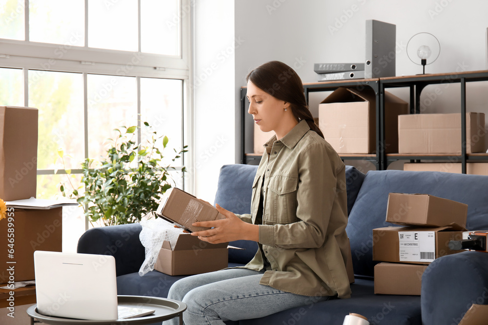 Young woman packing parcel for client at home