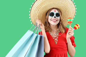 Young woman with painted skull, shopping bags and maracas on green background. Mexico's Day of the Dead (El Dia de Muertos) celebration