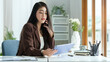 © wattana - Beautiful businesswoman talking on mobile phone and using digital tablet at desk.