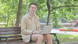 © stockbakers - Modern Young Man Smiling at Camera while Working on Laptop Outdoor