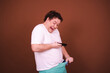Funny fat man takes indecent photos. A man has strong emotions. Brown background.
