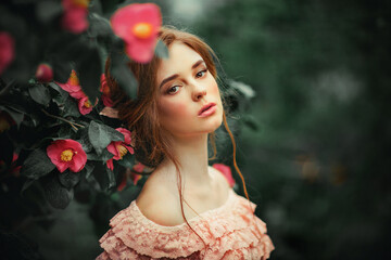 Portrait of a  beautiful red hair girl in a pink vintage dress standing near colorful flowers. Art work of romantic woman .Pretty tenderness model .