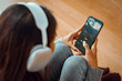 © oatawa - Woman with headphones holding mobile phone listening to music while sitting on the the sofa in living room at homes, Smiling girl relaxing with earphones in morning, Time to relax