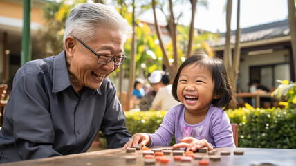 happy little girl with grandfather playing board game outdoors.