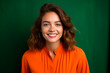 attractive young woman smiling dressed in orange on green background. created with AI