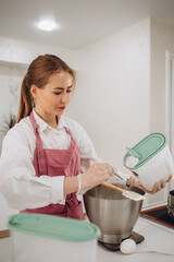 Wall Mural - woman confectioner prepares a cake in the kitchen at home. Home baking for the whole family. High quality photo