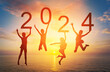 Happy new year card 2024. Silhouette of children girl is jumping on tropical beach with fantastic sunset sky background. Kids holding the number 2024 with sea and sunrise background.