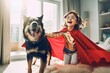 Happy kid and cute dog in superhero cloaks playing together at home indoor