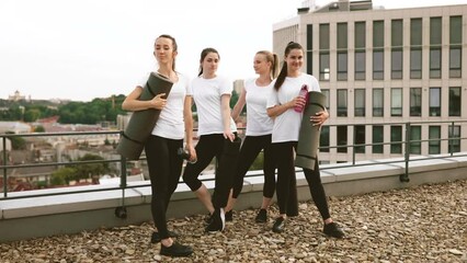 Wall Mural - Women posing with yoga mats and water bottles on rooftop