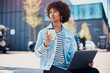 © Flamingo Images - Young woman working on a laptop over coffee on a city bench