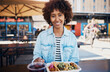 © Flamingo Images - Young woman smiling while eating tacos outside on the patio of a restaurant