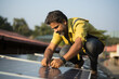 Indian technician installing solar panel over home roof in India