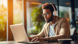 © ckybe - With a bright expression, a young African American gentleman in glasses and headphones sits comfortably with his laptop