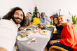 © Xavier Lorenzo - Happy multi generational family taking selfie portrait together sitting on table at dinner christmas celebration