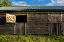 Old weather worn structure of wooden stables on farm in sunlight