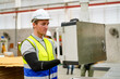 © FotoArtist - Industrial worker indoors in factory. Young technician with orange hard hat. Smart Caucasian factory worker wearing hardhat and working in power plant.
