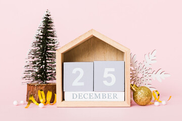 25 december. Christmas composition on colored background with a wooden calendar, with a gift box, toys, bauble copy space