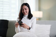 © PaeGAG - Happy young asian woman relax on comfortable couch at home texting messaging on smartphone, smiling girl use cellphone, chatting online message.
