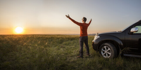 man traveling exploring, enjoying the view of the nature at sunrise. man standing near his car on vacation and watching the sunset at nature.