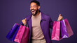 © Studio Nova - Happy smiling man holding shopping bags on purple background