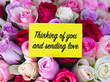 A yellow greeting card with words Thinking of You and Sending Love on a bouquet of colorful roses