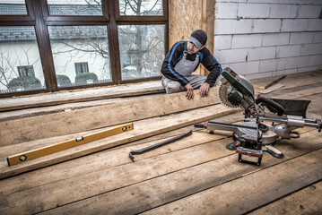 Wall Mural - Carpenter works with wooden board. Mitre saw