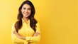 Confident young woman standing with her arms crossed on yellow background