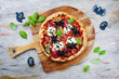 Traditionelle italienische Halloween Spinnen Pizza mit Salami, Mozzarella und Oliven serviert als Draufsicht mit Fledermaus und Geister auf einer Holz Pizzaschaufel