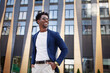 © Anna Zhuk - Confident african American male in stylish clothes stands in city next to modern building, looking to side with smile. Happy black man with hands in pockets