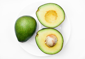 Wall Mural - Sliced green avocado on a white background. Pieces of green vegetable on a white plate. Delicious food for a vegan.