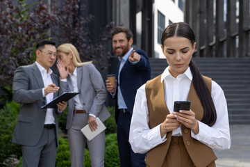 Bullying and Harassment at workplace in office, employees discussing with colleague on lunch break outside office building.