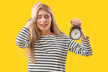 Wall Mural - Stressed young woman with alarm clock on yellow background. Deadline concept